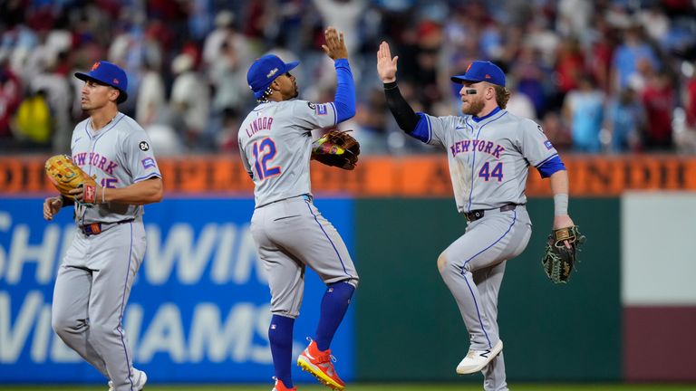 Harrison Bader (44) z New York Mets, Francisco Lindor (12) a Tyrone Taylor slaví vítězství v prvním zápase série baseballové divize NL proti Philadelphia Phillies, v sobotu 5. října 2024 ve Philadelphii. (AP Photo/Matt Slocum)