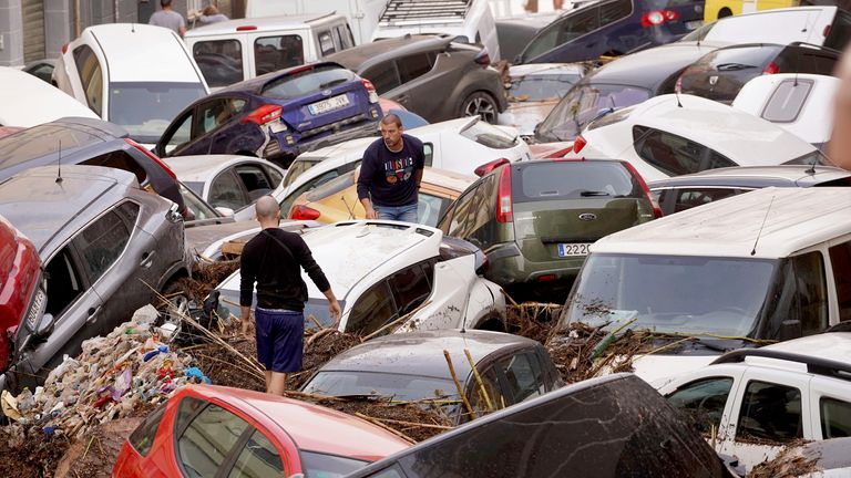 Obyvatelé se dívají na auta nahromaděná poté, co je smetly povodně ve španělské Valencii, ve středu 30. října 2024. (AP Photo/Alberto Saiz)