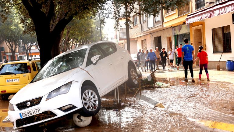 Lidé chodí po blátem pokryté ulici poté, co přívalové deště způsobily záplavy v La Alcudia.  Snímek: Reuters