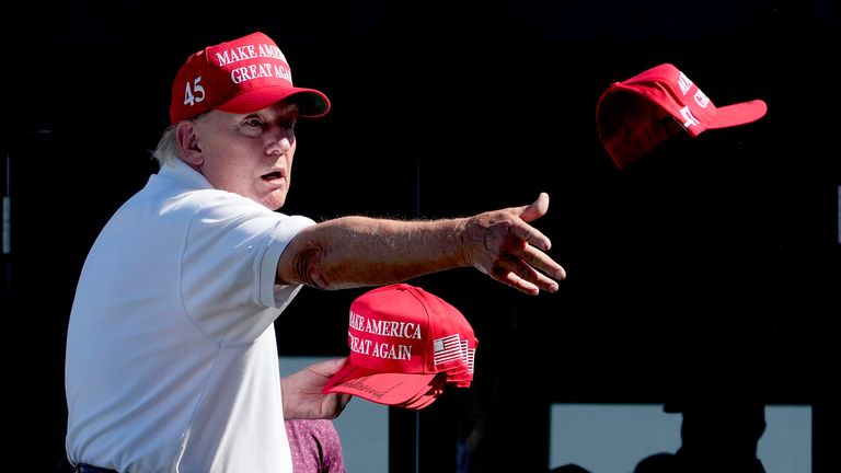 Donald Trump hází davu podepsané klobouky během posledního kola golfového turnaje Bedminster Invitational LIV v Bedminsteru.  Obrázek: AP