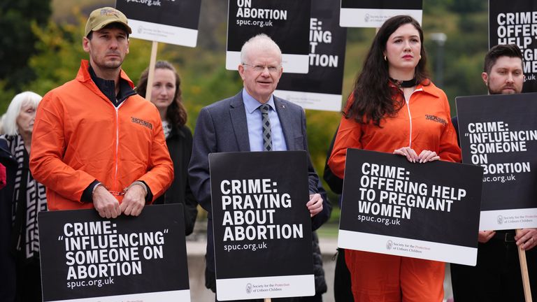 John Mason MSP se připojuje k lidem, kteří se účastní protestu před skotským parlamentem v Edinburghu, protože ve Skotsku vstupují v platnost nové zákony, které brání demonstrantům proti potratům shromažďovat se do vzdálenosti 200 metrů od zařízení, kde se provádějí potraty. Bezpečné přístupové zóny jsou ve 30 zdravotnických zařízeních po celém Skotsku. Datum snímku: úterý 24. září 2024.