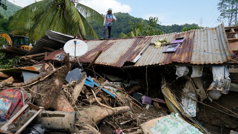 Marcelino Aringo stojí na vrcholu poškozeného domu poté, co sesuv půdy vyvolaný tropickou bouří Trami nedávno zasáhl Talisay, provincie Batangas, Filipíny, v sobotu 26. října 2024. (AP Photo/Aaron Favila)