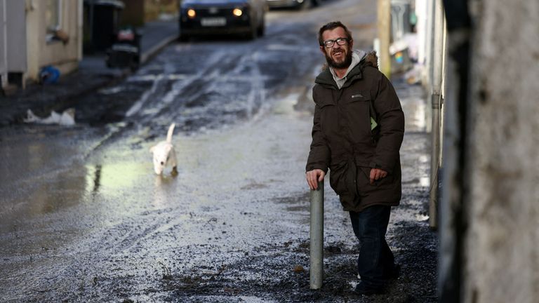 Obyvatel a pes pohybují bahnem bahnem v Cwmtillery ve Walesu.  Snímek: Reuters