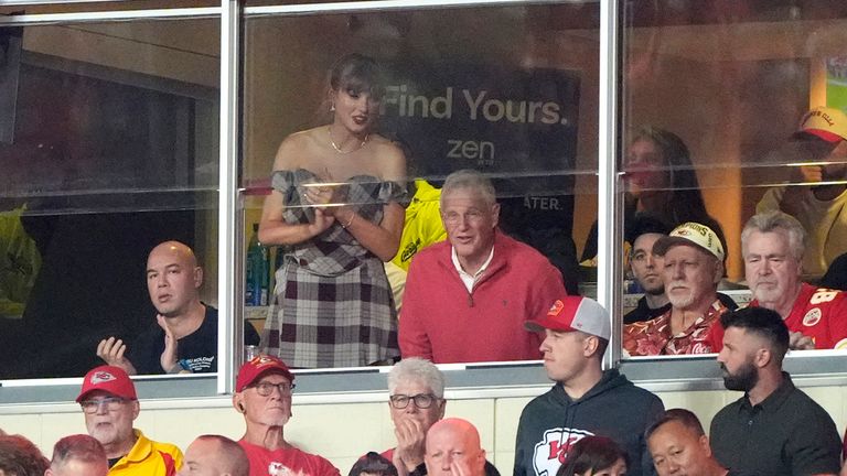 Taylor Swift stojí, když se dívá z apartmá vedle svého otce Scotta Swifta během první poloviny fotbalového zápasu NFL mezi Kansas City Chiefs a New Orleans Saints pondělí 7. října 2024 v Kansas City, Mo. (AP Foto/Charlie Riedel)