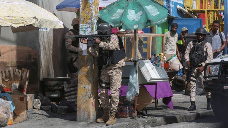 Policisté hlídkují na ulici během přestřelky mezi gangy a policií v Port-au-Prince na Haiti, pondělí 11. listopadu 2024. (AP Photo/Odelyn Joseph)