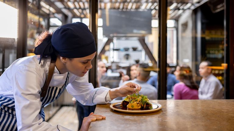 Kuchařka zdobení talíře v kuchyni v restauraci - koncepty zařízení pro jídlo a pití