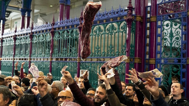 Butchers of G Lawrence Wholesale Meats draží maso návštěvníkům akce během vánoční aukce masa na trhu Smithfield Market na tržnici Grand Avenue v londýnské City, kdy obchodníci draží své přebytečné maso veřejnosti v tradici, která trvá již století. Datum fotografie: Sobota 23. prosince 2023.