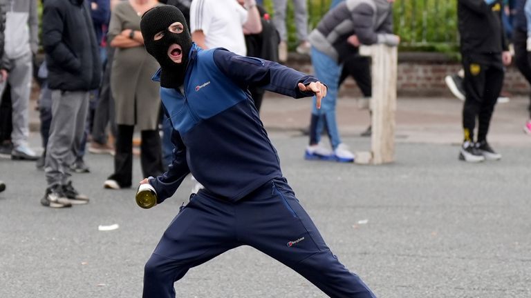 Mladík hází láhev na gardai důstojníky během stání s demonstranty poté, co bylo založeno několik požárů v bývalém areálu továrny Crown Paints v Coolock na severu Dublinu. Datum snímku: pondělí 15. července 2024. PA Foto. Demonstranti protestovali proti přestavbě nepoužívaného skladiště pro ubytování žadatelů o azyl. Viz příběh PA IRISH Coollock. Fotografický kredit by měl znít: Niall Carson/PA Wire