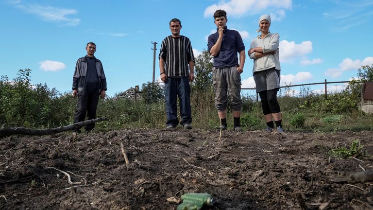 Ukrainians stand near an anti-personnel mine near their house in Kamyanka. Pic: Reuters