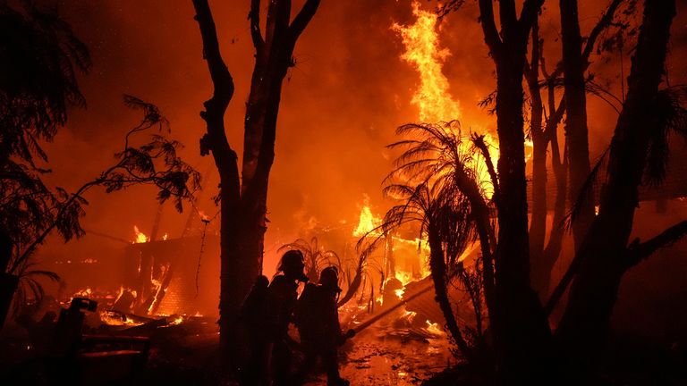 Hasiči stříkají vodu na dům, který hoří při požáru Franklin Fire v Malibu v Kalifornii, úterý 10. prosince 2024. (AP Photo/Jae C. Hong)