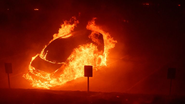 Vozidlo hoří během Franklin Fire v kampusu Pepperdine University v Malibu, Kalifornie, úterý 10. prosince 2024. (AP Photo/Eric Thayer)