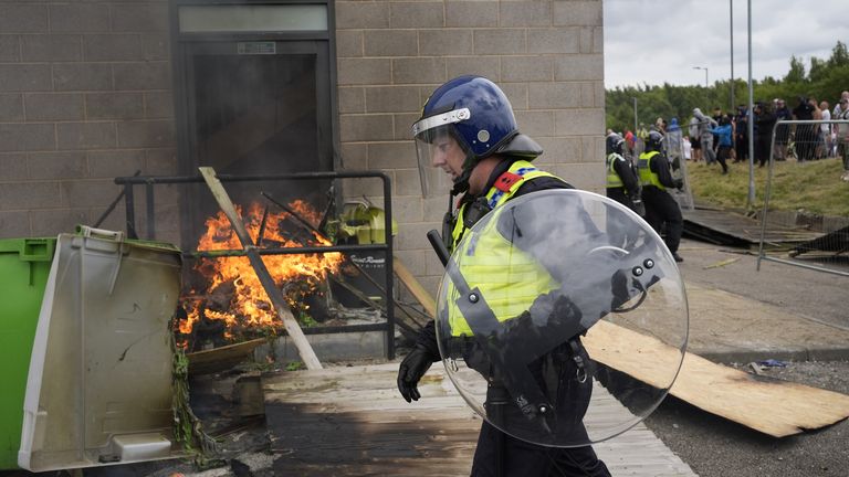 Policista prochází kolem požáru, když se během protestu proti imigraci před hotelem Holiday Inn Express v Rotherhamu v jižním Yorkshiru rozhoří potíže. Datum snímku: neděle 4. srpna 2024. PA 