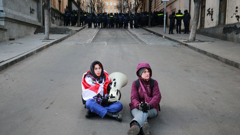 Gruzínští demonstranti sedí na ulici před policií.  Obrázek: AP