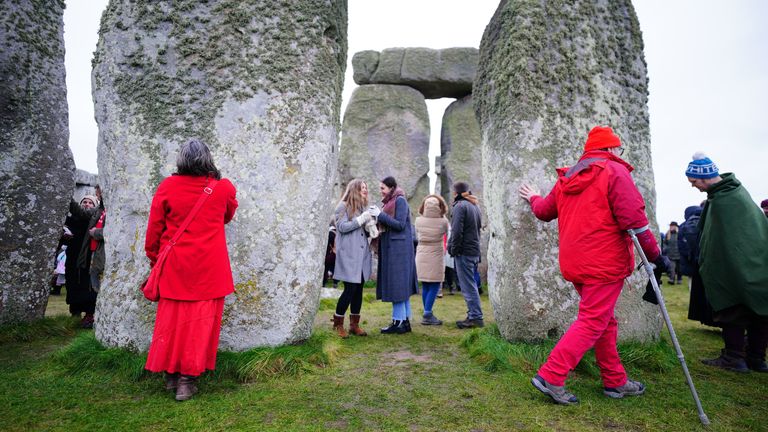 Lidé se účastní oslav zimního slunovratu během východu slunce u prehistorického monumentu Stonehenge na Salisbury Plain ve Wiltshire. Datum fotografie: čtvrtek 22. prosince 2022.