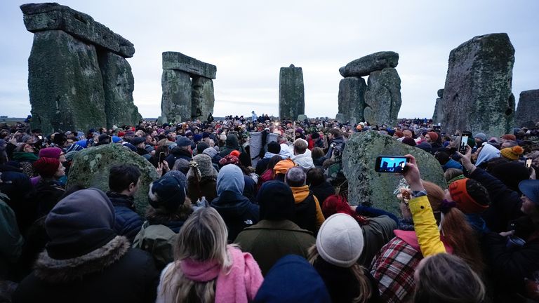 Lidé se účastní oslav zimního slunovratu během východu slunce u prehistorického monumentu Stonehenge na Salisbury Plain ve Wiltshire. Datum snímku: Sobota 21. prosince 2024.