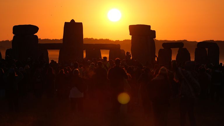 Lidé sledují východ slunce, když se účastní letního slunovratu ve Stonehenge.  Obrázek: PA