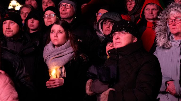 Lidé před magdeburskou katedrálou sledují v sobotu 21. prosince 2024 v německém Magdeburgu vzpomínkovou bohoslužbu za oběti pátečního útoku na vánoční trhy, kde auto vjelo do davu. (AP Photo/Ebrahim Noroozi)