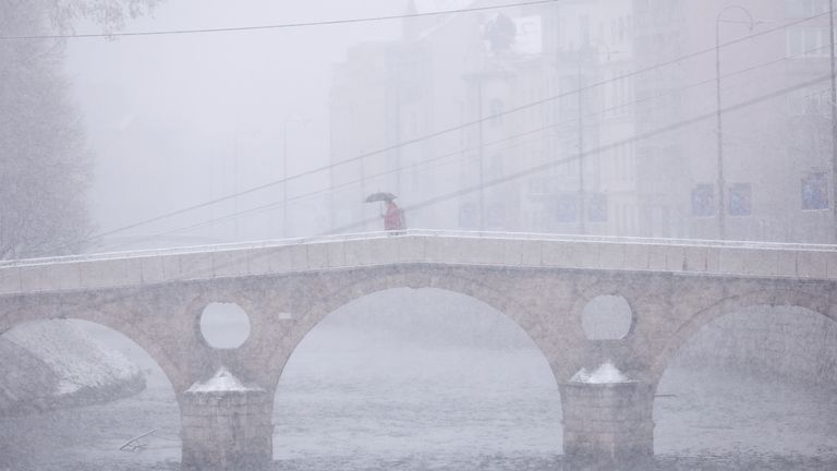 Muž jde přes most během hustého sněžení v centru Sarajeva v Bosně, pondělí 23. prosince 2024. (AP Photo/Armin Durgut)