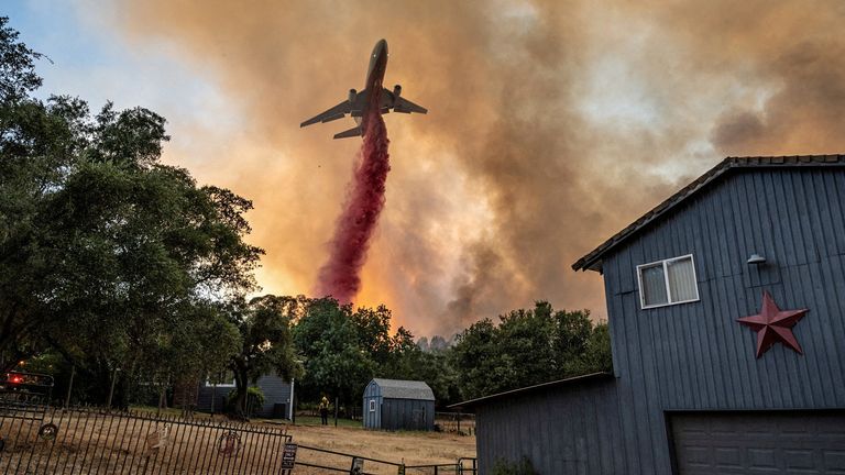 Firefighters drop retardant from a plane next to a house as they battle a wildfire in a canyon in Oroville, California, U.S., July 2, 2024. REUTERS/Carlos Barria        SEARCH "REUTERS BEST 2024" FOR THIS STORY. SEARCH "REUTERS YEAR-END" FOR ALL 2024 YEAR END GALLERIES.          TPX IMAGES OF THE DAY