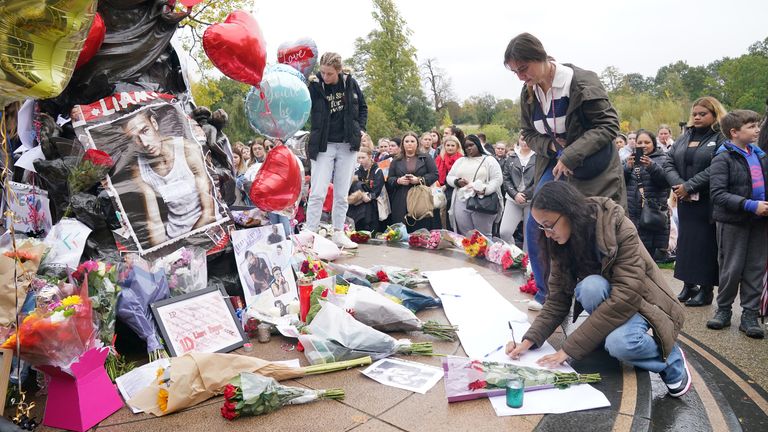 A person writing a message during a vigil for 31-year-old One Direction singer Liam Payne from Wolverhampton, at Hyde Park in central London. Payne, who rose to fame with the boy band on The X Factor, died after falling from a third floor balcony of the Casa Sur Hotel in the Argentine capital Buenos Aires on Wednesday. Picture date: Saturday October 19, 2024.