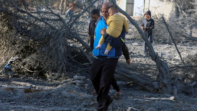 Palestinec s dítětem prochází na místě izraelského útoku na dům v Deir Al-Balah v centrálním pásmu Gazy.  Obrázek Reuters