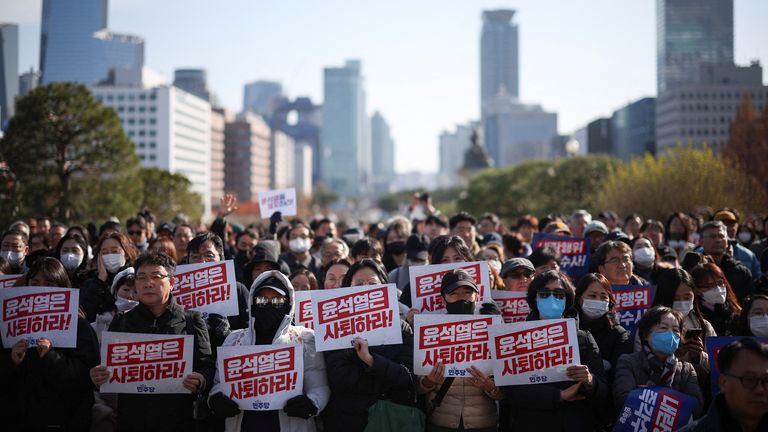 Demonstranti drží cedule s nápisem "Odstoupí prezident Yoon Suk Yeol" jak se lidé a zákonodárci účastní shromáždění k odsouzení překvapivého vyhlášení stanného práva jihokorejského prezidenta včera v noci a výzvy k jeho rezignaci na národním shromáždění v Soulu v Jižní Koreji dne 4. prosince 2024. REUTERS/Kim Hong-Ji