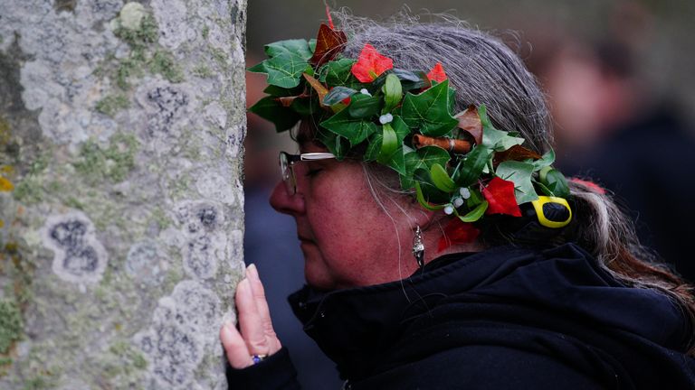 Lidé se účastní oslav zimního slunovratu během východu slunce u prehistorického monumentu Stonehenge na Salisbury Plain ve Wiltshire. Datum fotografie: čtvrtek 22. prosince 2022.