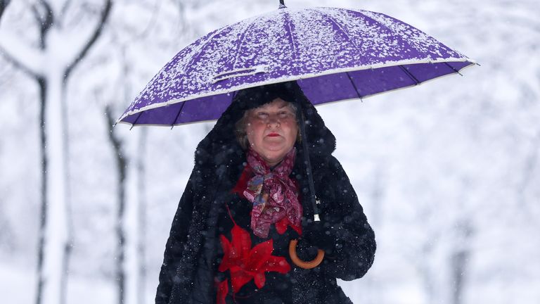 Žena prochází parkem během hustého sněžení v Sarajevu, Bosna, úterý 24. prosince 2024. (AP Photo/Armin Durgut)