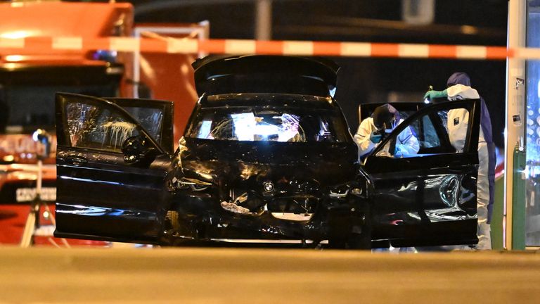 Kriminalisté na místě vyšetřují poškozené auto. Obr: Hendrik Schmidt/dpa přes AP