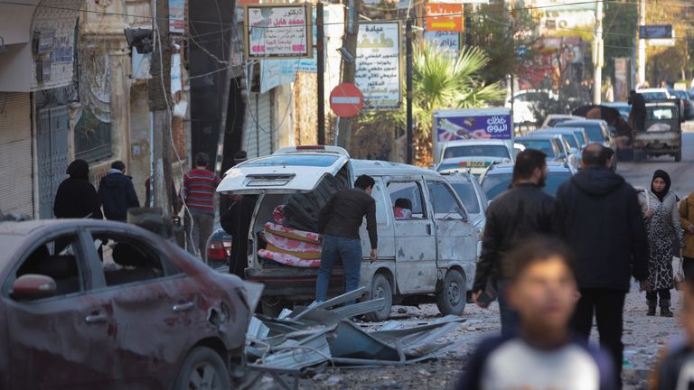 Lidé procházejí kolem poškozeného místa v Aleppu. Snímek: Reuters