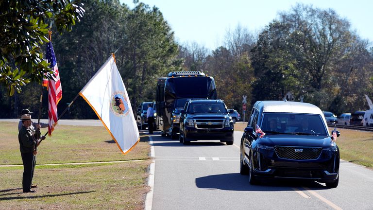 Členové National Park Service sledují, jak pohřební vůz s rakví Jimmyho Cartera projíždí jeho farmou z dětství v Archery ve státě Georgia. Snímek: Reuters