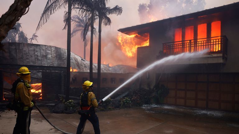 Hasiči hasí plameny, když Palisades Fire ničí rezidenci ve čtvrti Pacific Palisades v Los Angeles, úterý 7. ledna 2025. (AP Photo/Etienne Laurent)