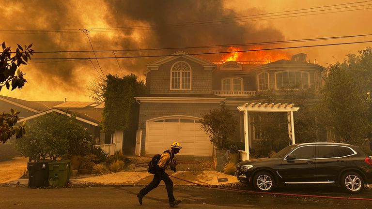 Rezidence hoří, když hasič bojuje s požárem Palisades ve čtvrti Pacific Palisades v Los Angeles úterý 7. ledna 2025. (AP Photo/Eugene Garcia)