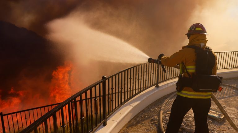 Hasič se postaví před postupující požár Palisades ve čtvrti Pacific Palisades v Los Angeles, úterý 7. ledna 2025. (AP Photo/Etienne Laurent)