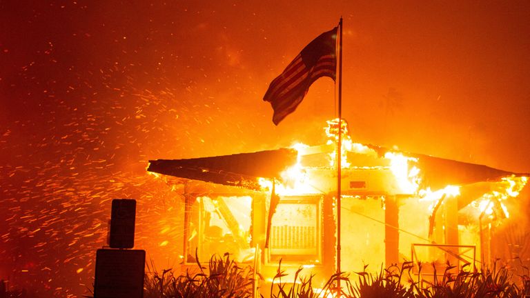 Americká vlajka vlaje, když oheň pohltí konstrukci, zatímco Palisádový oheň hoří během větrné bouře na západní straně Los Angeles v Kalifornii.  Snímek: Reuters