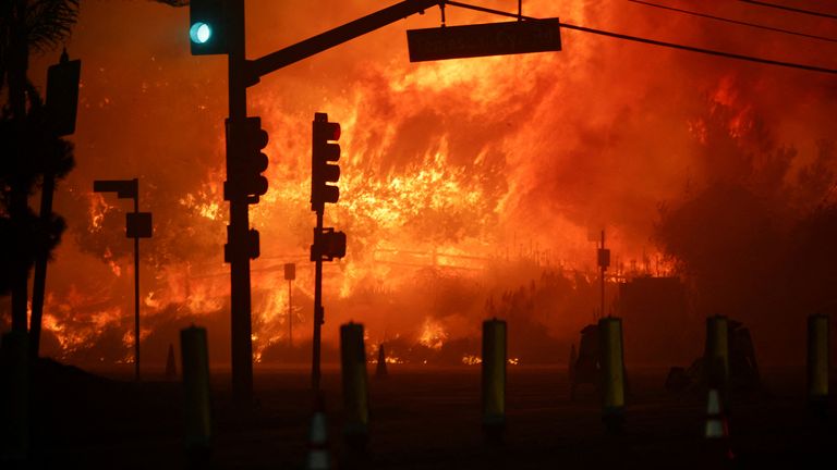 Signální světlo svítí zeleně na Pacific Coast Highway, když hoří lesní požár ve čtvrti Pacific Palisades na západě Los Angeles, Kalifornie, 7. ledna 2025. REUTERS/Daniel Cole TPX IMAGES OF THE DAY