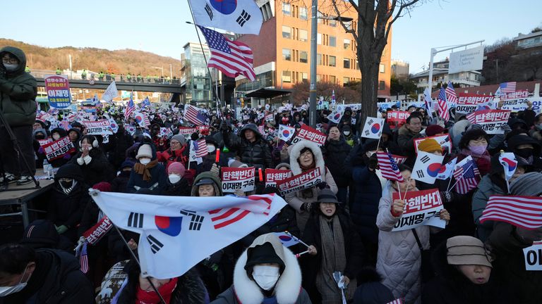 Příznivci obviněného jihokorejského prezidenta Yoon Suk Yeola pořádají shromáždění proti soudu, který vydal příkaz k zadržení Yoona, zatímco policejní úřady hlídají poblíž prezidentské rezidence v Soulu v Jižní Koreji v pátek 3. ledna 2025. "Postavit se proti impeachmentu." (AP Photo/Lee ​​Jin-man)