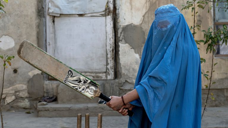 Afghánská žena pózuje na fotografii s kriketovou pálkou v Kábulu, Afghánistán, pátek 11. listopadu 2022. Vládnoucí Tálibán zakázal ženám sportovat a také jim zakázal většinu školní docházky a mnoha oblastí práce. Řada žen pózovala fotografovi agentury AP pro portréty s vybavením pro sporty, které milovaly. Ačkoli burky nutně nenosí v běžném životě, rozhodli se skrýt svou identitu svými burkami, protože se obávají represálií Talibanu a protože někteří z nich nadále tajně provozují své sporty. (AP Photo/Ebrahim Noroozi)