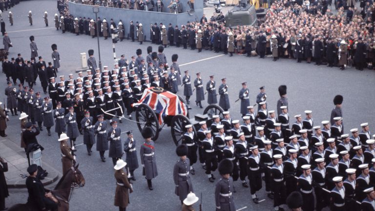 Námořní strana nakreslí kočár zbraní, nesoucí rakvi sira Winstona Churchilla, pomalu se pohybuje z Whitehall přes roh náměstí Trafalgar, během pohřebního průvodu do katedrály sv. Pavla, Londýna, 30. ledna 1965. (AP Photo)