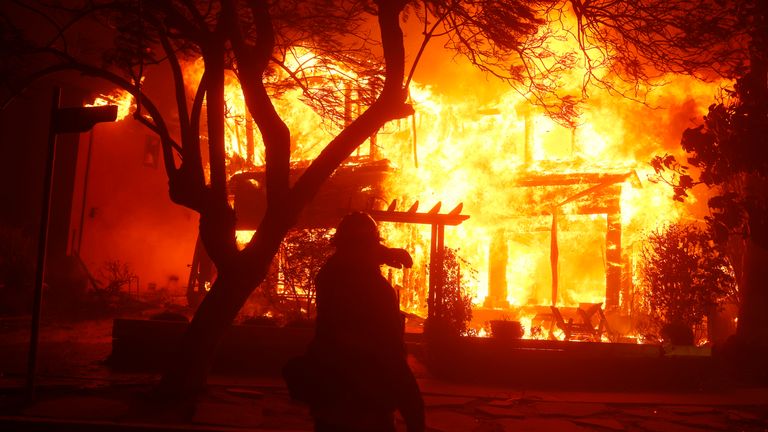 Hasič si chrání jejich obličej, když Palisades Fire spálí dům v Los Angeles. Obrázek: AP