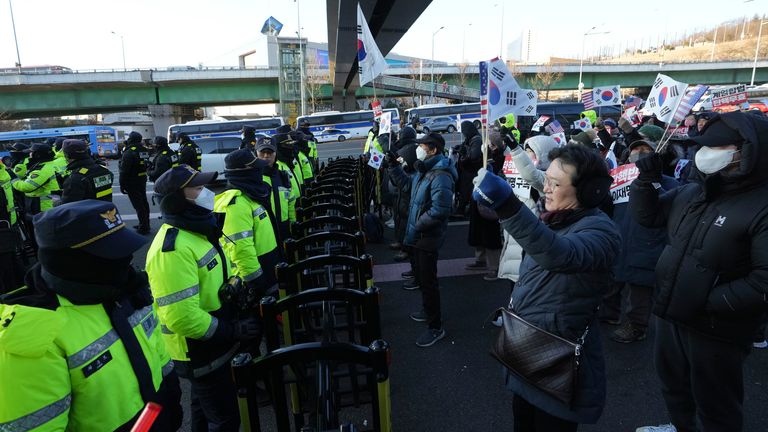 Příznivci obviněného jihokorejského prezidenta Yoon Suk Yeola pořádají shromáždění proti soudu, který vydal příkaz k zadržení Yoona, zatímco policejní úřady hlídají poblíž prezidentské rezidence v Soulu v Jižní Koreji v pátek 3. ledna 2025. "Postavit se proti impeachmentu." (AP Photo/Lee ​​Jin-man)