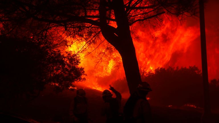 Hasiči nastupují před postupující požár Palisades ve čtvrti Pacific Palisades v Los Angeles, úterý 7. ledna 2025. (AP Photo/Etienne Laurent)