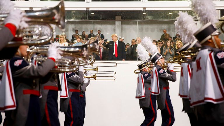 Pan Trump sleduje pochodující kapelu na Pennsylvania Avenue při své první inauguraci