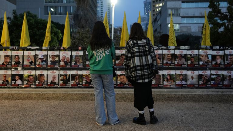 Dvě ženy si prohlížejí fotografie rukojmích držených v Gaze. Obrázek: AP Photo/Oded Balilty