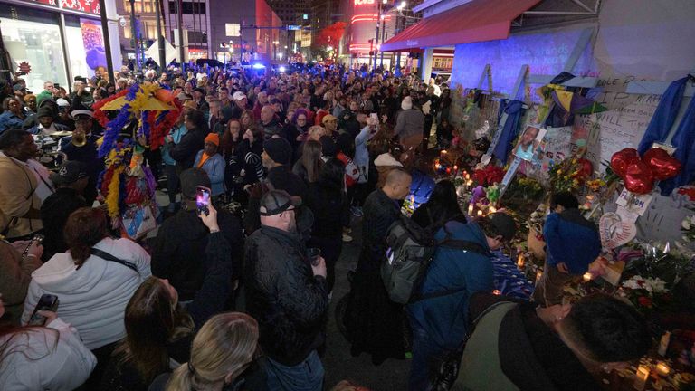 Lidé se v sobotu 4. ledna 2025 shlukují na Bourbon Street poblíž křižovatky Canal Street v New Orleans, když si připomínají oběti novoročního smrtícího útoku nákladním autem a střelby. (AP Photo/Matthew Hinton)