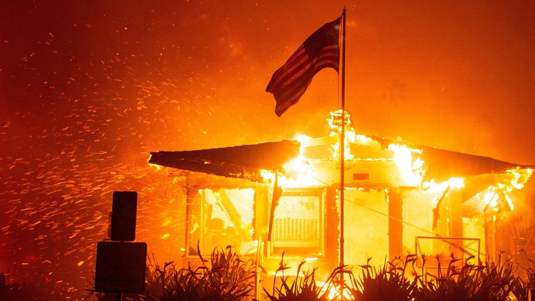 Americká vlajka vlaje, když plameny z požáru Palisades pohltí konstrukci během větrné bouře na západě Los Angeles. Snímek: Reuters