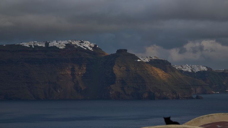 Kočka sedí na klenuté střeše ve městě Oia na ostrově zemětřesení v Santorini v Řecku, protože hlavní město Fira je vidět v pozadí v úterý 4. února 2025. (AP Photo/Petros Giannakouris)