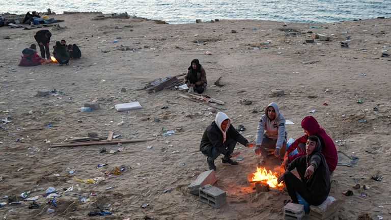 Vysídlení Palestinci se zahřáli ohněm, když čekají, až se vrátí do svých domovů v severní části pásma Gazy, neděle 26. ledna 2025, dny poté, co vstoupila v platnost dohoda o příměří mezi Izraelem a Hamasem. (AP Photo/Abdel Kareem Hana)