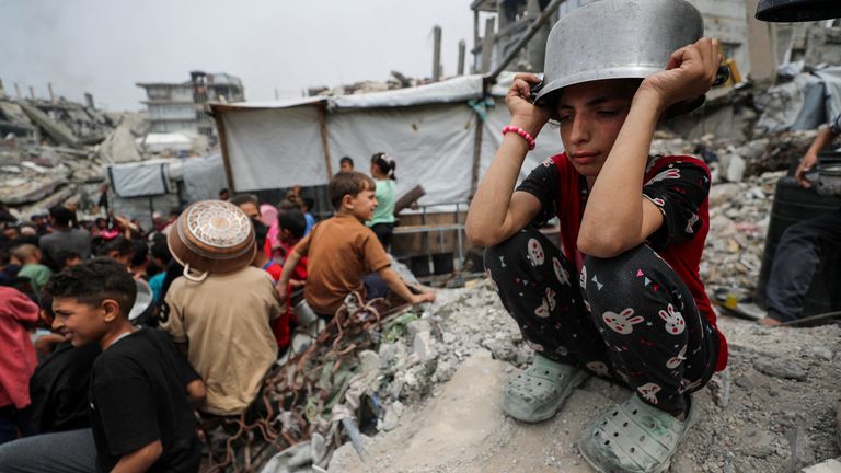Dívka čeká s ostatními Palestinci, aby obdržela jídlo vařené charitativní kuchyní v Beit Lahia, Severní Gaza Strip.  Pic: Reuters/Mahmúd Issa