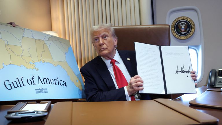 U.S. President Donald Trump holds up a proclamation renaming the Gulf of Mexico to the Gulf of America, while flying over the gulf aboard Air Force One en route to New Orleans to attend the Super Bowl, February 9,  2025. REUTERS/Kevin Lamarque